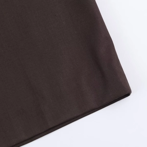 Vue détaillée de l'ourlet du pantalon marron foncé montrant la texture du tissu fin