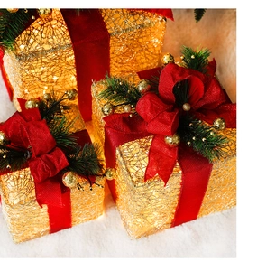 Detail of warm LED Christmas gift boxes with red bows and pine cones on a snowy rug