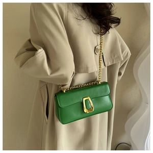 Detail of green leather shoulder bag featuring gold chain strap and U-shaped metal lock