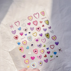 Detail of colorful 3D heart nail stickers with small rhinestones on a soft background