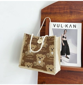 Detail of a brown canvas bear tote bag hanging on a wooden rack with magazines