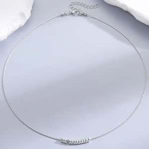 Macro shot of silver pearl necklace with faceted beads and lobster clasp on rock decor