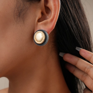Nahaufnahme der geometrischen runden Beflockungs-Ohrstecker in Gold und Grau am Modell