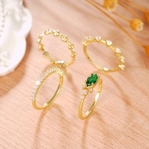 Detalle de cuatro anillos dorados apilables con circón verde y diseño de textura de hoja