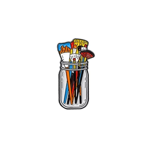 Artistic metal enamel pin featuring colorful paintbrushes in a glass jar design
