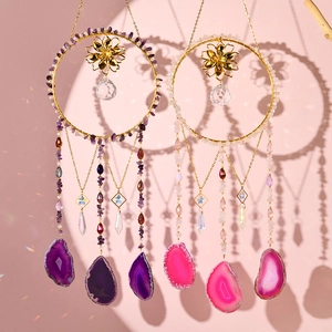 Macro shot of purple and pink crystal suncatchers with agate slices and golden moon frames