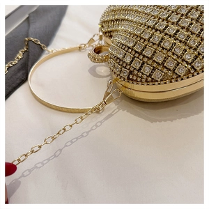 Close-up of heart-shaped gold evening bag featuring dense rhinestones and metal ring handle