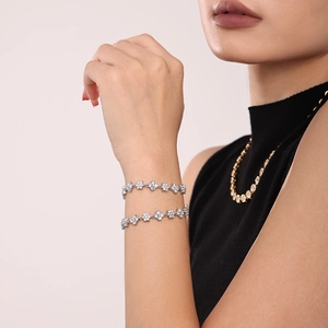 Silver flower bracelet with cubic zirconia inlay on a model's wrist, 18k gold plated finish