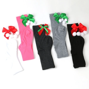 Detail of Christmas over-the-knee socks with satin bows and white fuzzy pom-poms