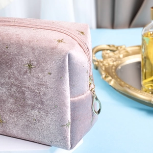 Detail of pink velvet makeup bag with gold star embroidery and heart zipper pull