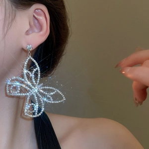 Detail shot of a large silver butterfly drop earring with brilliant rhinestones on model
