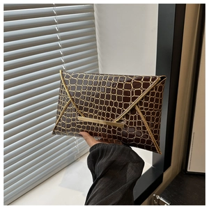 Detail of dark brown crocodile-embossed envelope clutch with gold metal V-shaped trim