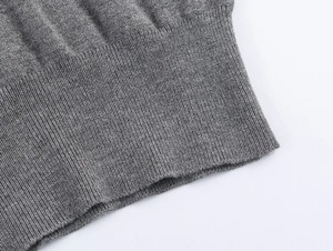 Macro shot of gray knitted cardigan detail showing ribbed cuff texture and fine weaving