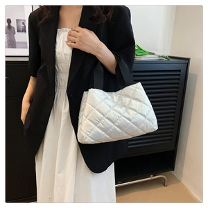 Détail d'un sac cabas rembourré blanc avec poignées noires et texture matelassée brillante