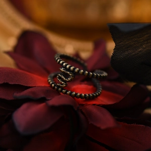 Artistic close-up of retro bronze snake ring nestled in dark red floral background