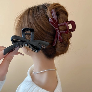 Detail of elegant black and burgundy bow hair claws for women with glossy finish