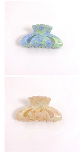 Close-up of shell-shaped acrylic hair claws with blue and pink marble textures