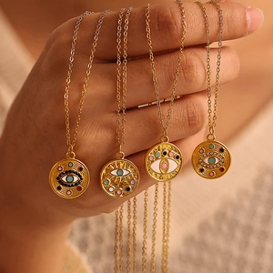 Colliers dorés avec pendentifs œil en émail multicolore présentés dans la main