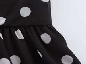 Détail macro d'une robe française à pois montrant la texture du mousseline plissée noire
