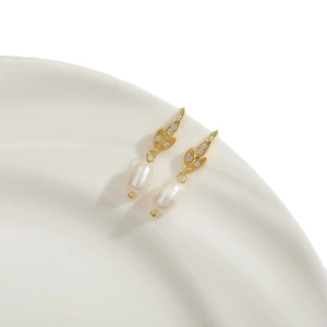 Elegant gold leaf earrings with freshwater pearls and cubic zirconia on ceramic tray