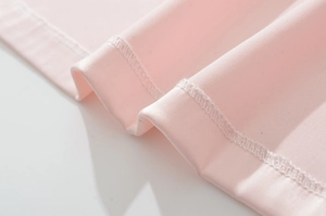 Macro detail of pink satin dress fabric showing smooth texture and fine overlock stitching