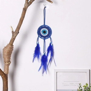 Detail eines blauen Traumfängers mit bösem Blick, Federn und Perlen an der Wand