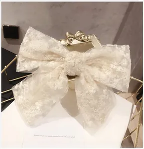 Close-up of floral embroidery on cream lace bow hairclip with layered mesh details