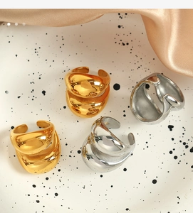 Detailed view of four 18K gold and silver chunky irregular open rings on a white tray