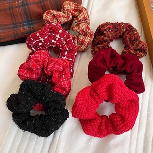 Knitted and tweed scrunchie set in red and black tones on white fabric background