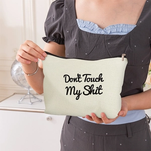 Portable canvas makeup bag with Don't Touch My Shit text held by a model in a home setting