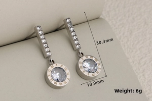 Macro detail of silver tassel earrings with Roman numerals and sparkling crystals
