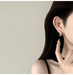 Close-up of 14k gold plated stud earrings with cubic zirconia and delicate pearl detail