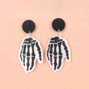 Close-up of gothic skull hand earrings with glitter black studs on orange background