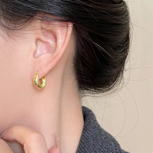 Close-up of minimalist 18K gold-plated U-shaped hoop earrings worn on a female ear