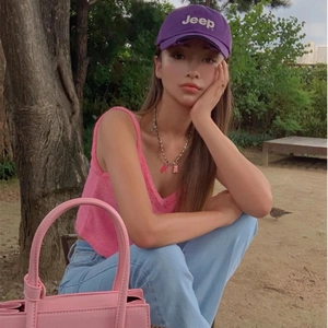 Close-up of a women wearing a purple Jeep baseball cap with pink knit vest and beads necklace