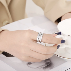 Close-up of triple-layered stainless steel ring with white shell inlays on model's hand