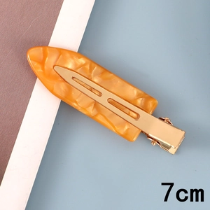 Detail view of a 7cm orange marble resin hair clip with gold metal duckbill base