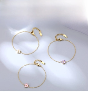 Three elegant gold-plated stainless steel bracelets with white, purple, and pink floral charms