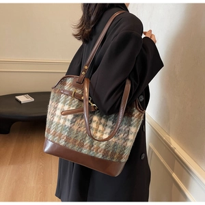 Side view of large retro plaid tote bag featuring brown leather trim and metal buckle