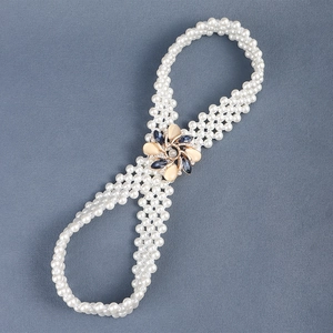 Detail of elastic pearl waist chain with beige floral buckle and navy blue gemstone