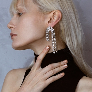 Exaggerated silver asymmetric U-shaped earrings with cascading rhinestones on a model