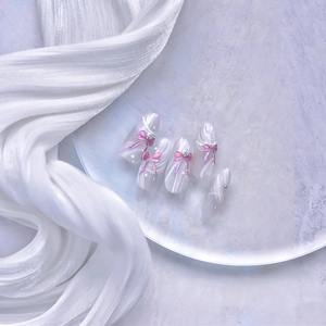 Détail de nœuds roses et perles sur ongles adhésifs jelly avec motifs étoiles argent