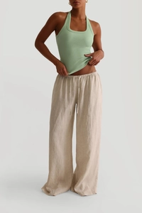 Nahaufnahme des grünen Y2K Halter-Tops mit beiger Leinenhose mit weitem Bein am Model