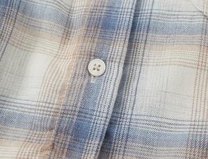 Vista macro dettagliata del tessuto della camicia a quadri con bottone crema