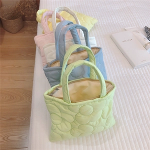 Dettaglio di mini borse trapuntate a fiori in vari colori pastello su un letto bianco