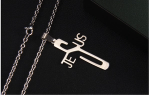 Detailed macro view of the silver Jesus cross pendant on black leather surface