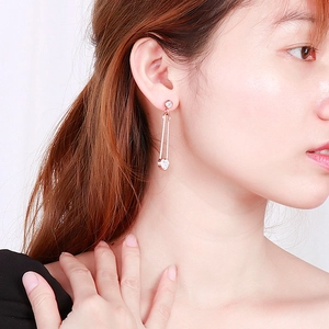 Vue détaillée des boucles d'oreilles trombone en or rose avec pendentif coeur en cristal