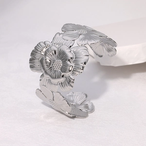 Dettaglio macro del bracciale rigido in acciaio con motivi floreali 3D e petali lucidi