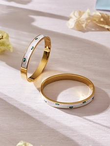 Detail of 18k gold plated stainless steel evil eye bangles with white enamel and turquoise