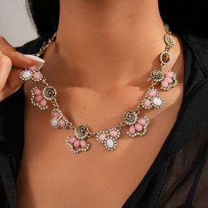Detailed view of vintage gold necklace with pink resin flowers and crystal inlay